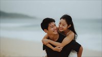 Young Asian couple embracing on beach at sunset, romantic moment by ocean waves, love and relationship concept for wedding or engagement content.