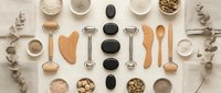 Spa wellness beauty tools flat lay with natural skincare products, massage stones, wooden utensils and organic ingredients on neutral background.