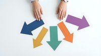 Business hands arranging colorful directional arrows on white background for decision making and strategic planning concepts.