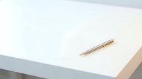 Elegant gold pen lying on clean white paper surface with soft natural lighting creating minimalist workspace atmosphere for business and writing concepts.
