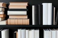 Books arranged on dark wooden shelves in minimalist style, featuring neutral tones of white and beige spines creating modern aesthetic composition for library or study space.
