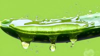Fresh cucumber slice with water drops falling and splashing against bright green background, macro photography showing crisp details and transparency.