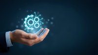 Businessman hand holding glowing gear icon with connected nodes on dark blue background, representing digital innovation, technology solutions, and business process automation.