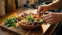 Hands of a person preparing a fresh salad bowl with mixed greens, grains, and vegetables on a wooden cutting board in a home kitchen setting.