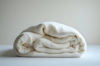 Folded white fleece blanket on neutral background showing soft texture and cozy layers, minimalist composition for home decor and comfort concepts.