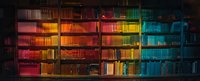 Colorful rainbow gradient bookshelf in dark library interior with vintage books arranged by color from red to blue creating atmospheric literary backdrop.