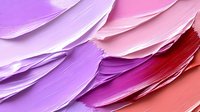 Vibrant makeup smears in pink, purple and red tones create dynamic diagonal strokes showing cosmetic texture and pigment swatches for beauty and fashion design.