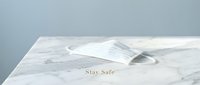 White medical face mask on marble surface with Stay Safe text, health protection concept for pandemic awareness and safety campaigns.