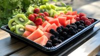 Fresh cut fruit platter with watermelon, kiwi, strawberries and blackberries arranged on black serving tray, bright natural lighting, healthy summer snack.