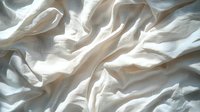 Soft white fabric with natural folds and creases creating abstract patterns and shadows in gentle light. Textural background for design projects.