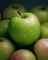 Fresh green apples with water droplets in dramatic lighting, showing natural texture and dewdrops on smooth skin, creating appetizing fresh produce composition.