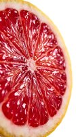 Fresh red grapefruit slice macro closeup showing juicy pulp texture and vibrant citrus segments on white background for food and health design.
