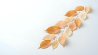 Paper craft autumn leaves in warm orange and beige tones arranged in curved line on white background for seasonal decoration and design projects.