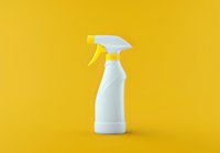 White plastic spray bottle on vibrant yellow background. Clean minimal composition with empty container for cleaning products, detergents or cosmetics.