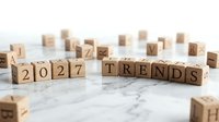 Wooden letter blocks spelling 2027 TRENDS on marble surface with scattered alphabet cubes, representing future forecasting and business planning concepts.