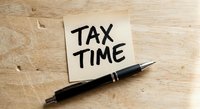 Tax time reminder note with black pen on wooden desk surface for accounting and financial planning preparation during filing season.