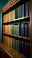 Wooden bookshelf with colorful vintage books arranged by color gradient from orange to blue creating rainbow effect in library or study room.