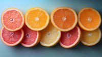 Fresh citrus fruits cut in halves showing vibrant pink grapefruit and orange slices arranged in row pattern on blue background, healthy vitamin C food concept.