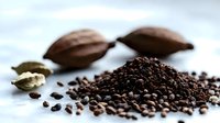 Fresh roasted coffee beans scattered on light surface with cardamom pods, creating aromatic composition for coffee shop menu or food packaging design.
