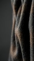 Close-up of draped charcoal gray wool fabric with soft folds and texture, suitable for fashion, textile, and interior design projects.