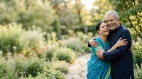 Senior couple embracing outdoors in lush garden setting, mature man and woman enjoying quality time together in nature, perfect for lifestyle and relationship content.