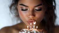 Young woman blowing out birthday candles on cake with warm candlelight glow. Celebration moment with closed eyes and peaceful expression for party themes.