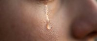 Close-up of emotional tear drop on human skin showing raw emotion and vulnerability for mental health awareness campaigns and therapeutic content.
