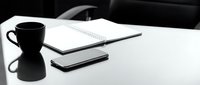 Minimalist black and white workspace with coffee mug, smartphone, and open spiral notebook on a clean white desk for business concepts.