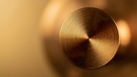 Golden metallic circular surface with radial brushed texture creating elegant concentric pattern against warm blurred background for luxury design projects.