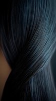 Silky smooth black hair strands flowing in elegant curves against dark background, showcasing natural shine and healthy texture for beauty and haircare advertising.