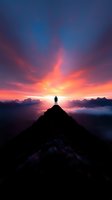 Silhouette of person standing on mountain peak at dramatic sunset with vibrant orange sky and clouds below, symbolizing achievement and personal growth.