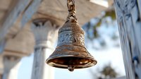 Ornate bronze bell with decorative patterns hanging from classical architecture, shallow depth of field creates artistic blur effect in background.