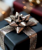 Elegant black gift box with sparkling gold glitter bow and ribbon against soft bokeh background, perfect for holiday or celebration themes.