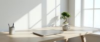 Minimalist wooden desk workspace with laptop, coffee cup and plant by bright window with natural sunlight creating geometric shadows on wall.