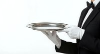 Professional waiter in black tuxedo and white gloves holding silver serving tray, hospitality service concept for restaurants and fine dining establishments.
