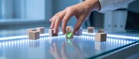 Hand placing wooden cube with glowing green checkmark on illuminated glass surface among scattered cubes, symbolizing approval and quality control.