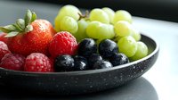 Fresh mixed berries and grapes in rustic bowl on wooden table. Healthy organic fruit selection with strawberries, raspberries, blueberries for breakfast or snack.