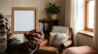 Person holding empty wooden frame in cozy living room interior with natural light, suitable for home decor, art display, and interior design projects.