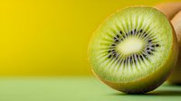 Fresh ripe kiwi fruit cut in half showing juicy green flesh and black seeds on vibrant yellow and green background, macro food photography.