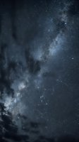 Stunning night sky with Milky Way galaxy and constellation patterns visible through dramatic clouds for astronomy and space exploration backgrounds.