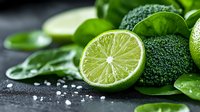 Sliced lime with fresh broccoli and herbs on dark surface, ideal for healthy cooking, nutrition, and food styling projects.