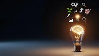 Glowing light bulb with brain inside surrounded by business icons representing innovation, creativity and strategic thinking for corporate success.