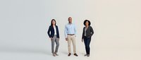 Diverse professional business team of three confident colleagues standing together in modern corporate attire on clean white studio background.