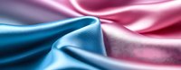 Luxurious smooth silk fabric in pink and blue colors with gentle folds and waves creating soft gradient effect, elegant textile background for fashion design.