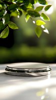Empty round metal platform display stand under green leaves on blurred natural background. Sunlight creates soft shadows for product photography.