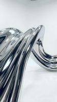 Abstract chrome liquid metal waves flowing in smooth curves with reflective surface creating modern futuristic design element for contemporary projects.