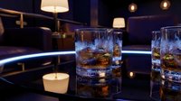 Glasses of whiskey with ice cubes on a dark reflective surface in a luxury lounge setting with ambient lighting and modern decor for bar, restaurant, and hospitality design.