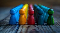 Colorful wooden game pieces arranged in row symbolizing diversity, teamwork and leadership concept. Perfect for business presentations and social topics.