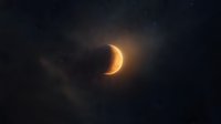 Glowing crescent moon illuminated against dark night sky with ethereal light halo and wispy clouds creating mystical celestial atmosphere.