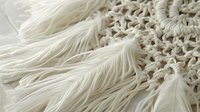 Delicate white feather macro photography showing intricate details and soft texture against light background, creating ethereal and dreamy atmosphere.